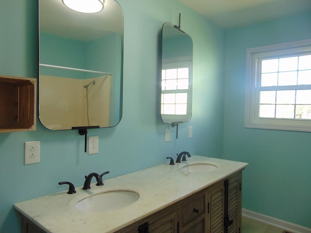 bathroom featuring double vanity, baseboards, and a sink