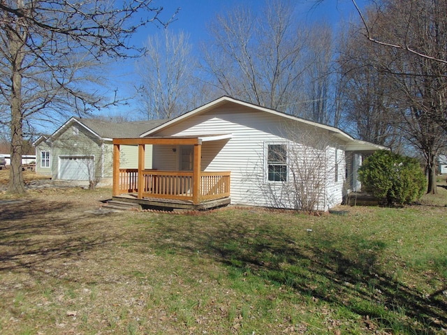 rear view of property featuring an attached garage, a yard, and a wooden deck