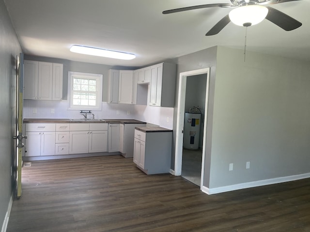 kitchen featuring baseboards, dark wood-style flooring, a sink, water heater, and backsplash