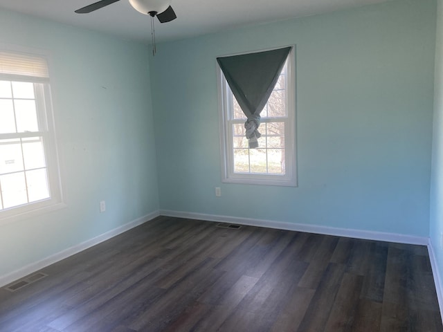 empty room with a healthy amount of sunlight, visible vents, and dark wood-style flooring