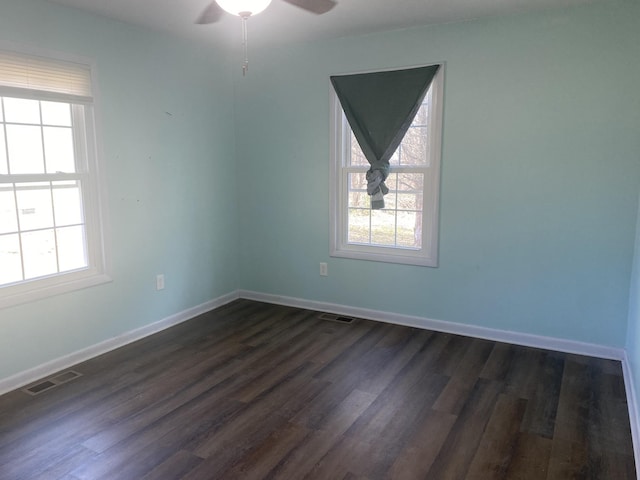 empty room with a ceiling fan, baseboards, visible vents, and dark wood-type flooring