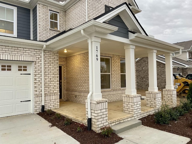 view of exterior entry featuring a garage, covered porch, and brick siding