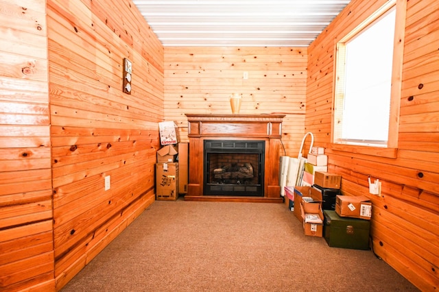 living area with a fireplace with raised hearth, wood walls, and carpet flooring