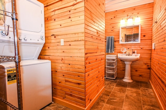 laundry room featuring stacked washer / dryer, laundry area, and wooden walls