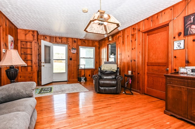 living area featuring a textured ceiling, wood walls, and light wood-type flooring