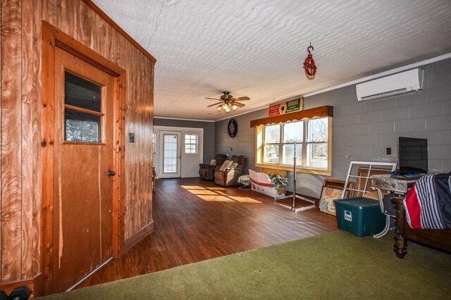 interior space featuring concrete block wall, ceiling fan, wood finished floors, a textured ceiling, and an AC wall unit