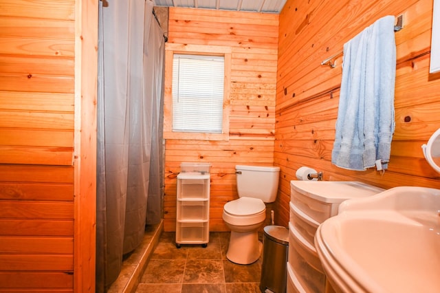 full bath featuring wooden walls, a sink, toilet, and a shower stall