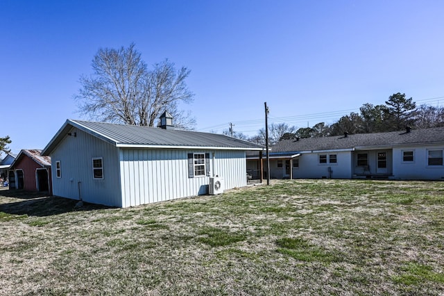 back of property featuring metal roof, a chimney, ac unit, and a lawn