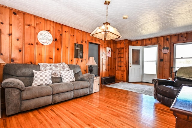 living area featuring a textured ceiling, wood walls, and light wood-style floors