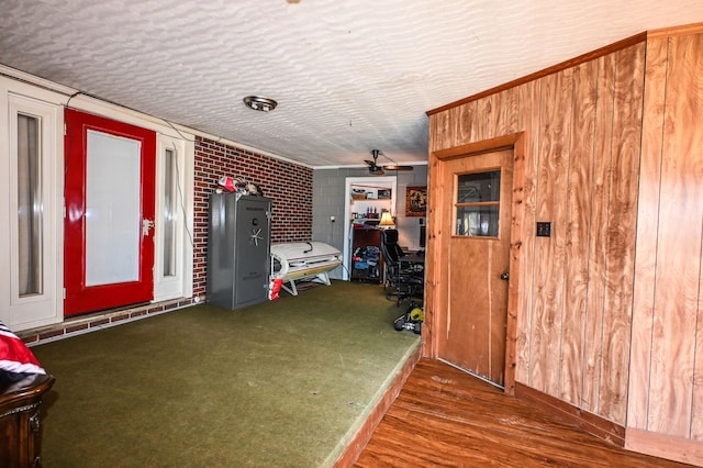 interior space featuring carpet floors, ceiling fan, a textured ceiling, and brick wall