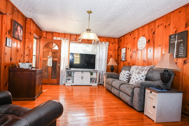 living area with plenty of natural light, light wood-type flooring, and wooden walls