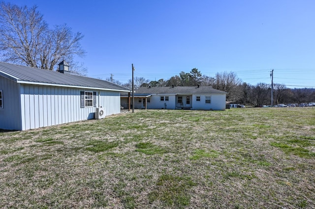 back of property with metal roof and a yard