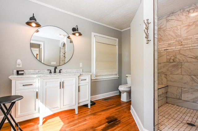 full bath with crown molding, toilet, vanity, wood finished floors, and baseboards