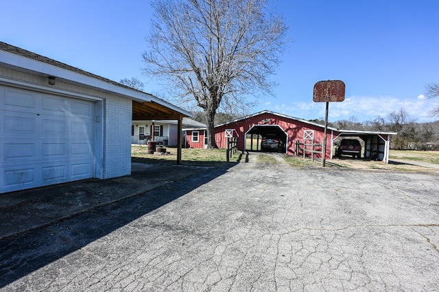 exterior space featuring an outbuilding, aphalt driveway, a garage, brick siding, and a pole building