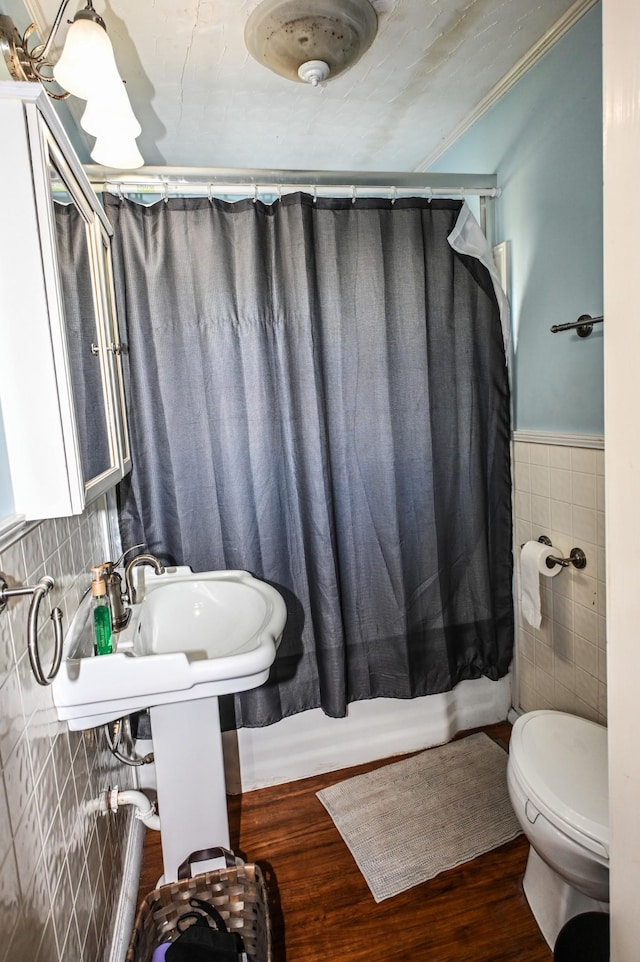 full bathroom featuring toilet, a wainscoted wall, wood finished floors, crown molding, and tile walls