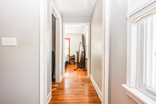 corridor featuring light wood-type flooring and baseboards