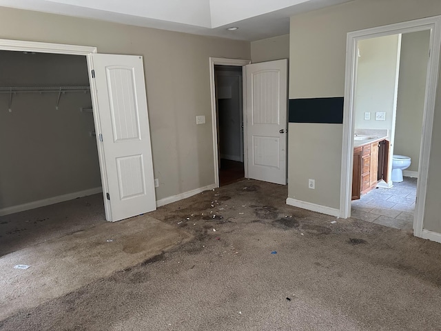 unfurnished bedroom with carpet flooring, a sink, ensuite bath, and baseboards