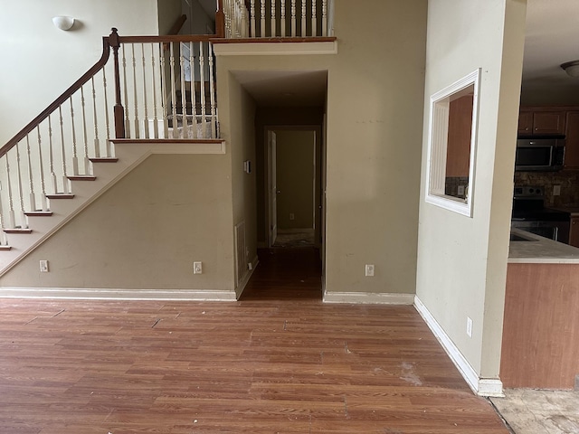 staircase with a high ceiling, baseboards, and wood finished floors