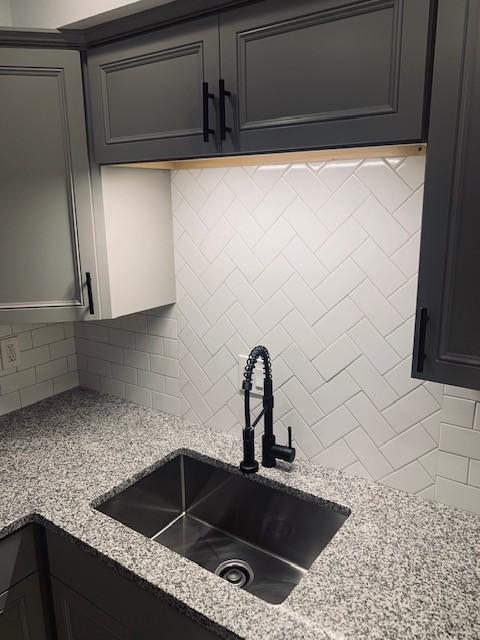 kitchen featuring a sink, decorative backsplash, and light stone countertops