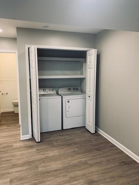 washroom featuring dark wood-style floors, laundry area, washing machine and dryer, and baseboards