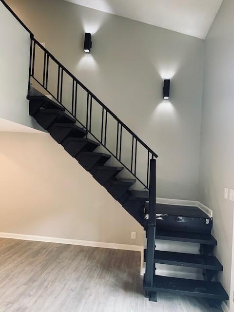 stairway with lofted ceiling, baseboards, and wood finished floors