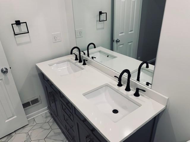 bathroom featuring marble finish floor, visible vents, and a sink