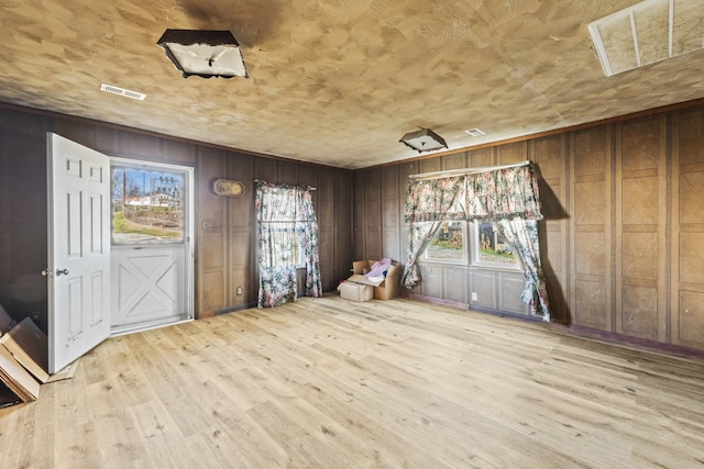 unfurnished room featuring visible vents, wooden walls, and wood finished floors