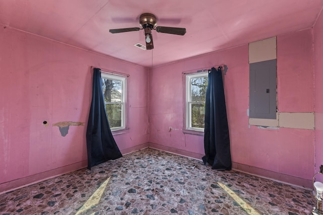 spare room with a ceiling fan, electric panel, plenty of natural light, and visible vents