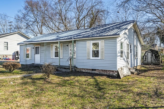 view of front facade featuring an outbuilding, metal roof, a storage shed, crawl space, and a front lawn