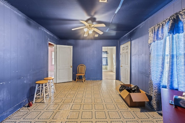 unfurnished room featuring wood walls, a ceiling fan, and tile patterned floors