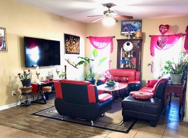 living room with baseboards, a ceiling fan, and wood finished floors