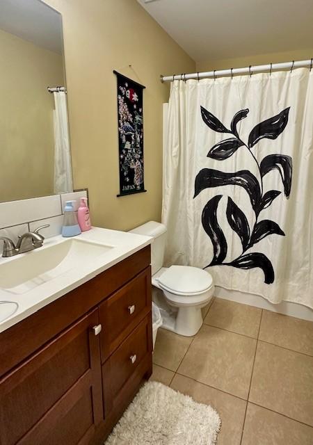 bathroom with curtained shower, vanity, toilet, and tile patterned floors