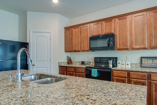 kitchen featuring brown cabinets, a sink, and black appliances