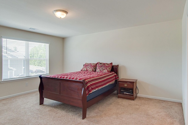 bedroom featuring baseboards, visible vents, and light colored carpet