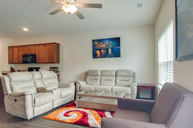 living area with ceiling fan, visible vents, and wood finished floors