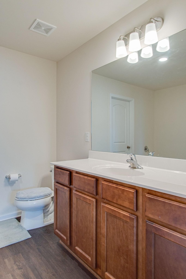 bathroom with visible vents, vanity, toilet, and wood finished floors