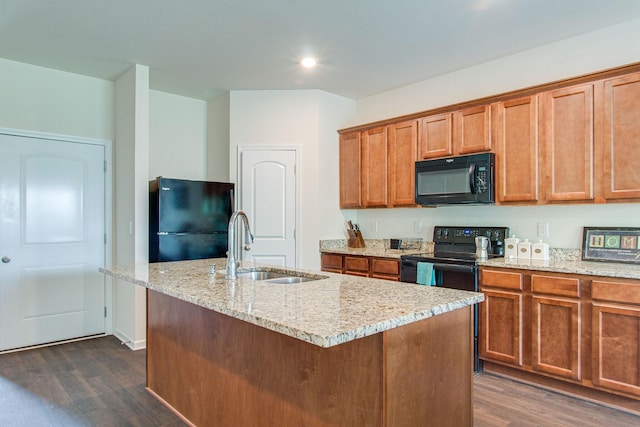 kitchen featuring a sink, dark wood finished floors, black appliances, and light stone countertops