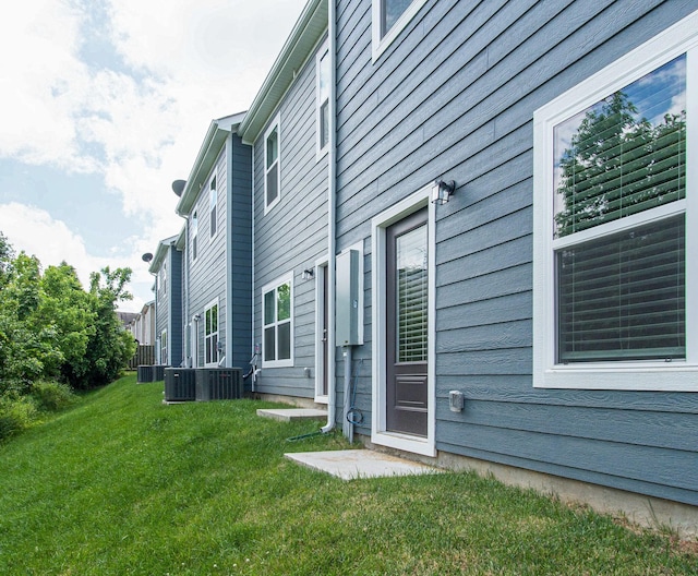 view of side of home with central AC and a yard