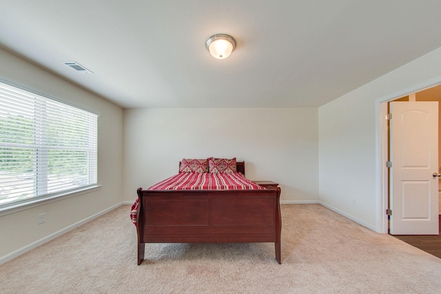 bedroom with baseboards, visible vents, and light colored carpet