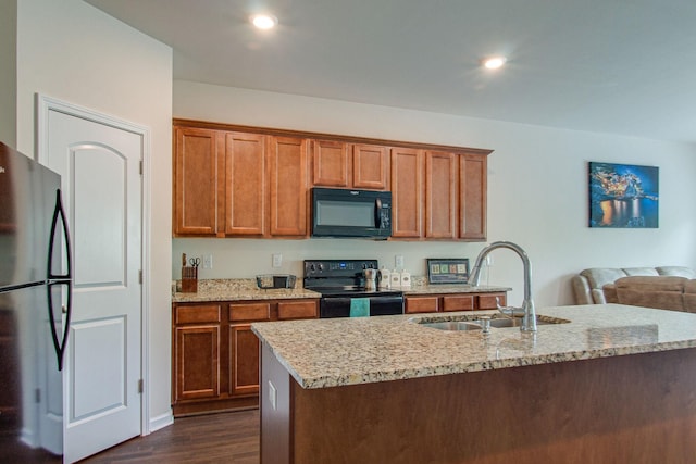 kitchen featuring light stone countertops, black appliances, brown cabinetry, and a sink