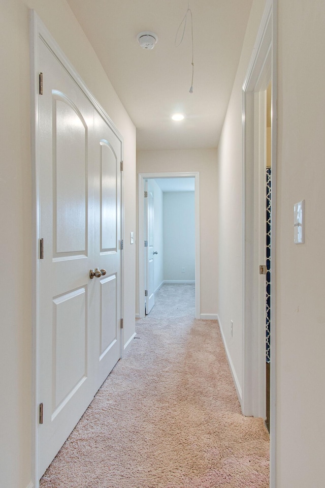 corridor with baseboards and light colored carpet