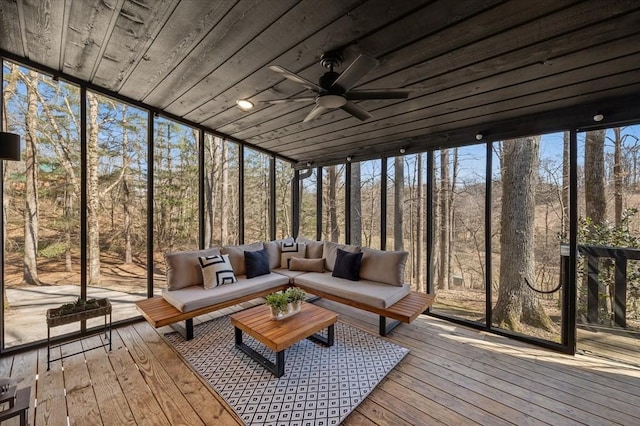 unfurnished sunroom with a forest view, wood ceiling, and a ceiling fan