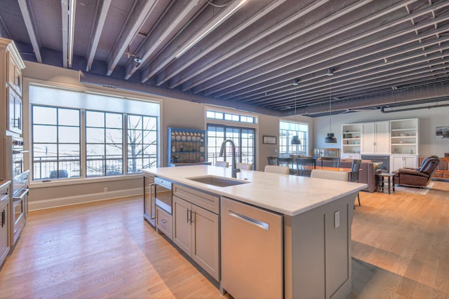 320 Liberty Pike Unit 212, Franklin, TN 37064 - kitchen with light wood finished floors, stainless steel appliances, a center island with sink, a sink, and gray cabinetry