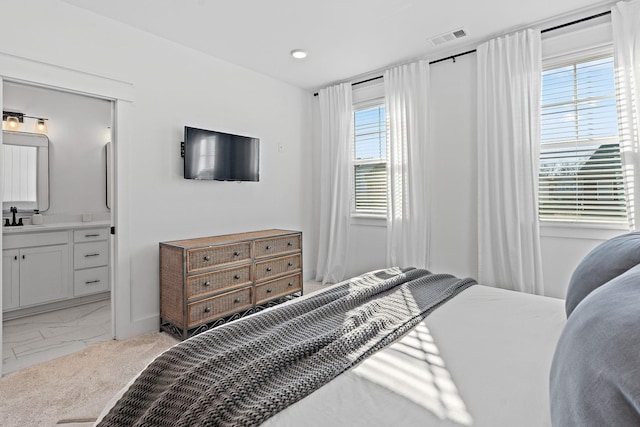 bedroom featuring marble finish floor, ensuite bath, a sink, and visible vents