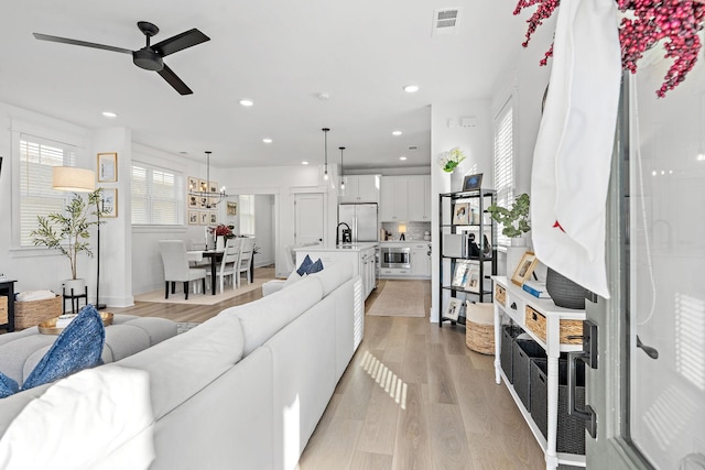 living room featuring light wood-style floors, recessed lighting, visible vents, and a ceiling fan