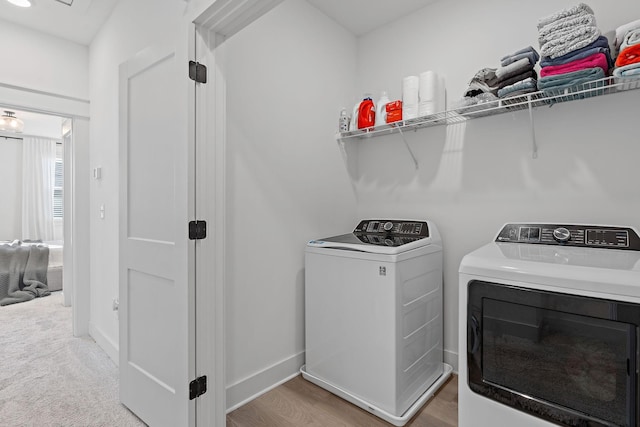 washroom with laundry area, baseboards, washer and clothes dryer, and light wood finished floors