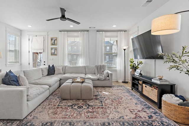 living area featuring a wealth of natural light, visible vents, and wood finished floors