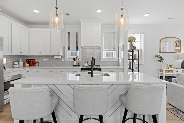 kitchen featuring tasteful backsplash, a breakfast bar area, a sink, and visible vents