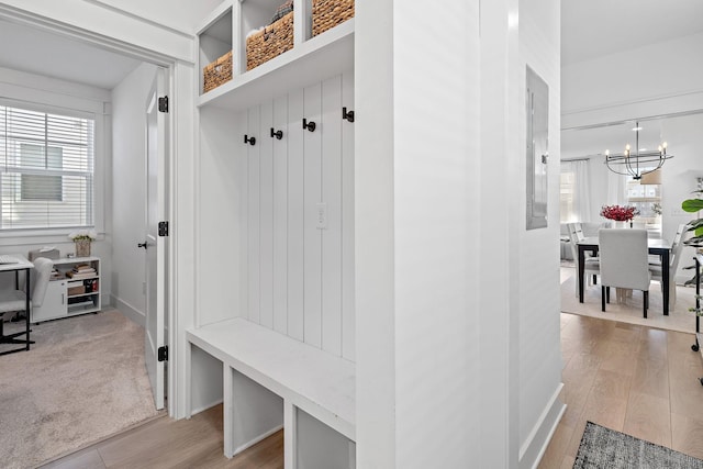 mudroom with light wood finished floors, plenty of natural light, and an inviting chandelier