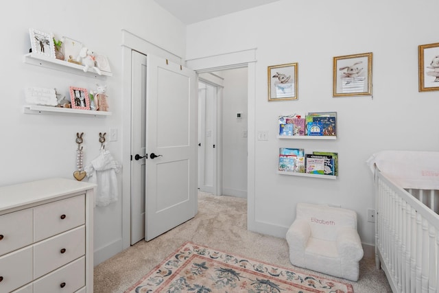 bedroom featuring a crib, baseboards, and light colored carpet